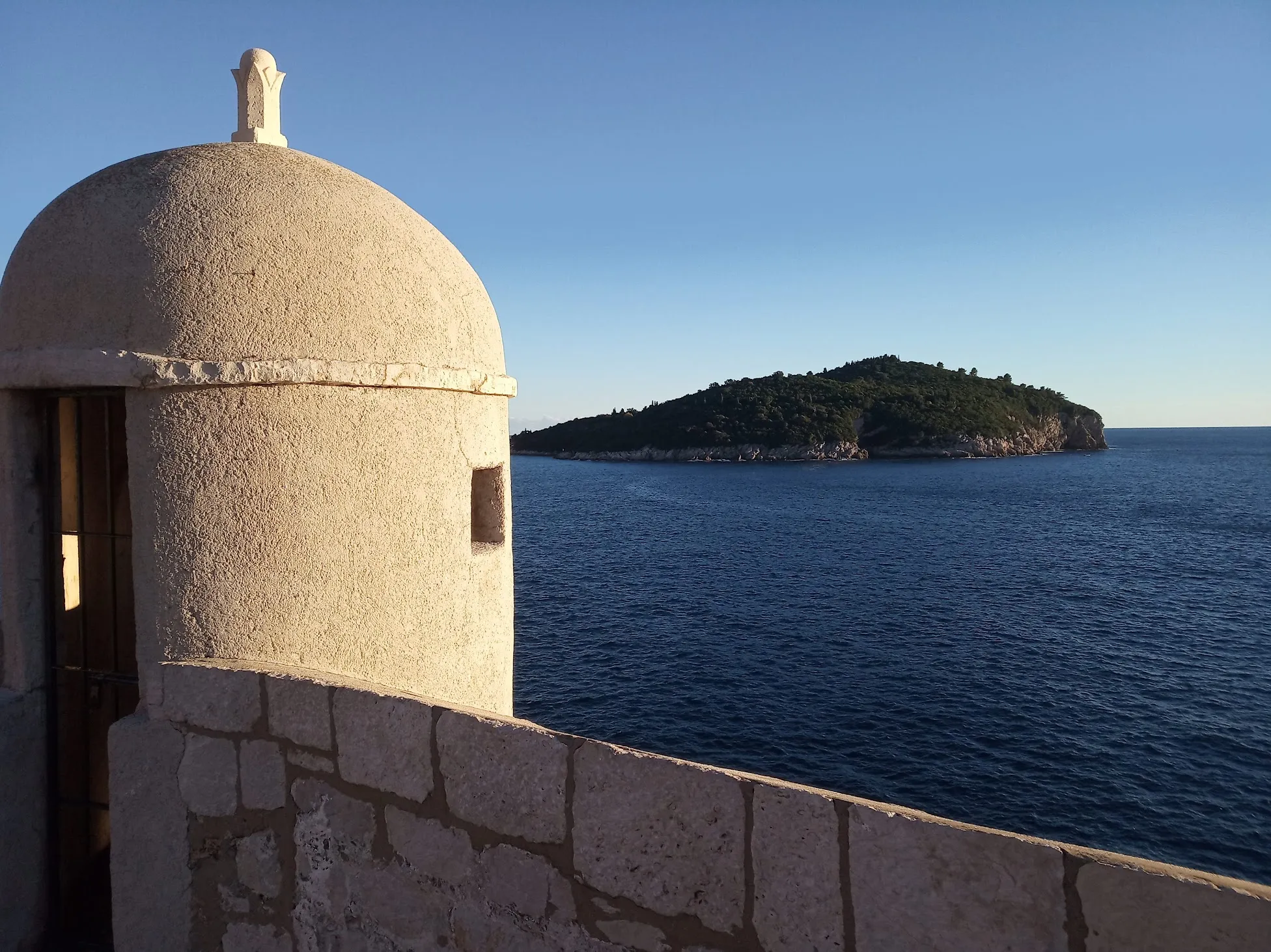 A round stone lookout on Dubrovnik's city walls, with Lokrum island across the sea